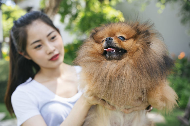 Young woman holding dog standing at park