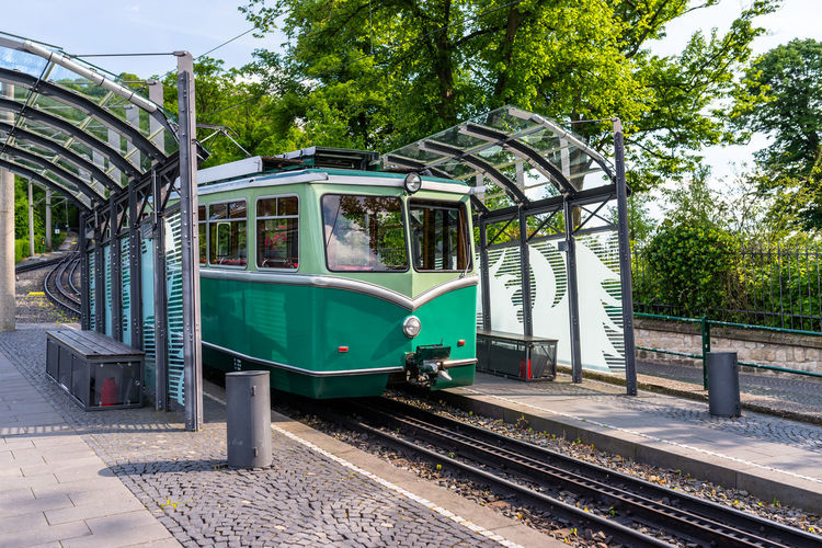 A green cog railway car standing on the tracks at the bus stop.