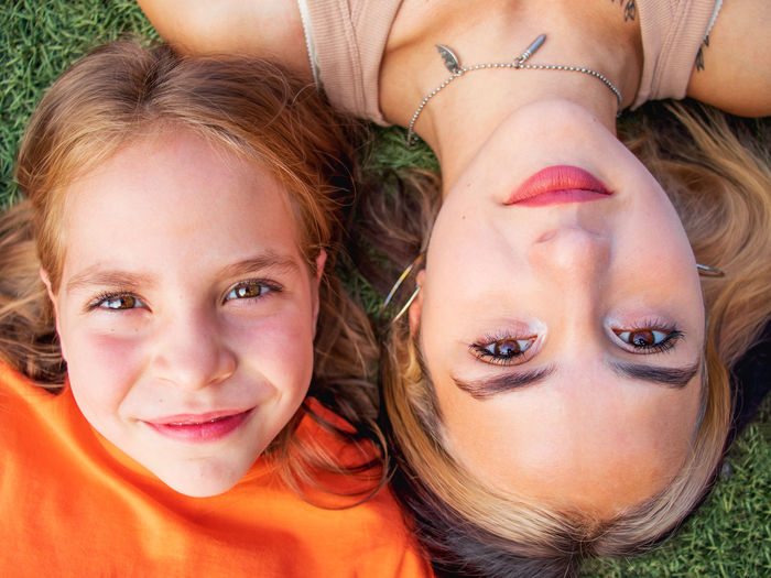 Two girls lie on the grass, smile and look at the camera, childhood