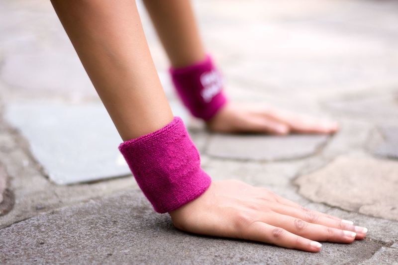 Cropped hands of woman with wristbands exercising on footpath
