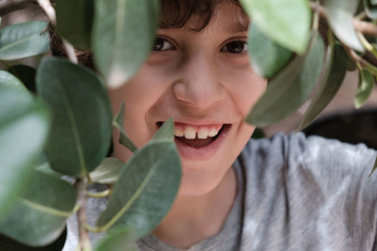 Close-up portrait of smiling girl with leaves