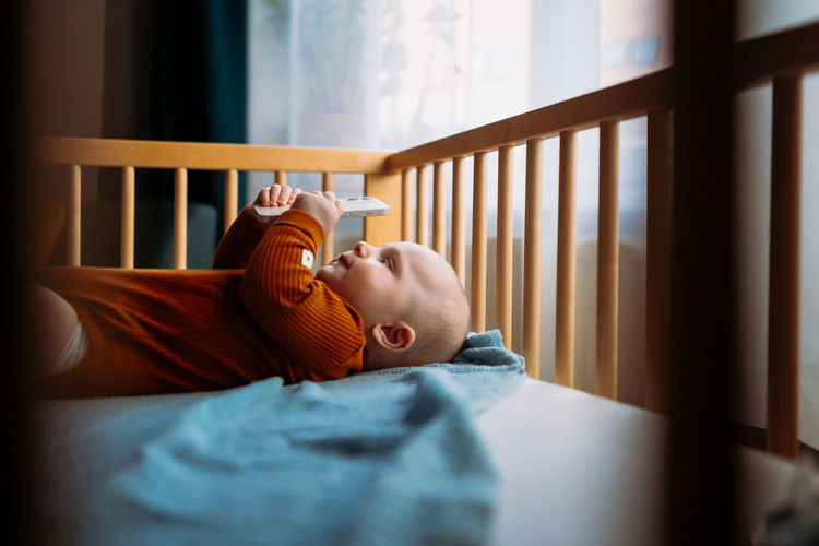 Cute boy holding mobile in crib