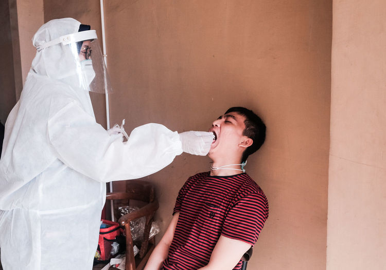 Doctor wearing protective suit examining patient at home