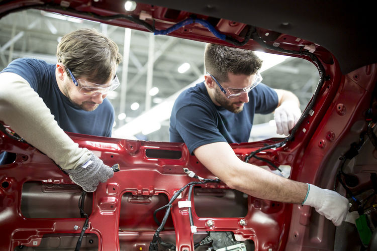 Two colleagues working at bodywork in modern car factory