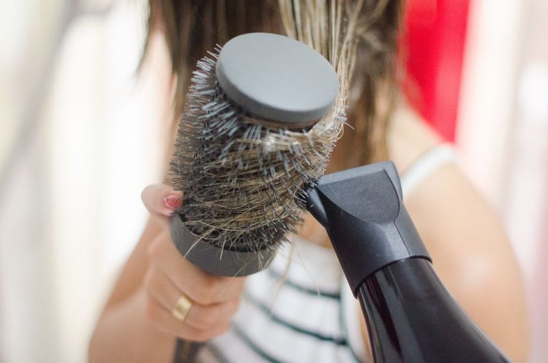 Close-up of woman drying hair with dryer