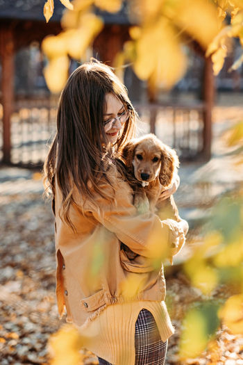Caring for your pet in autumn, cute english cocker spaniel puppy walking with female owner in
