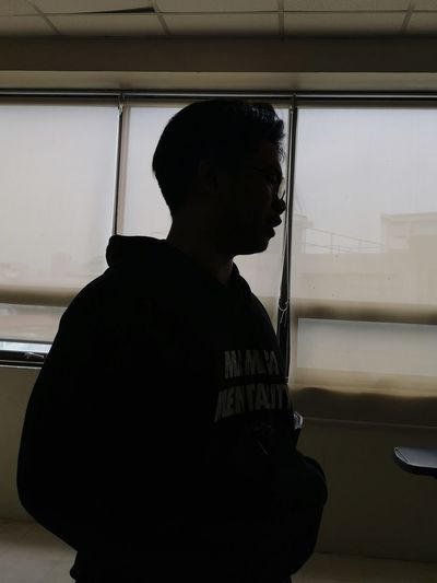 Side view of young man looking through window
