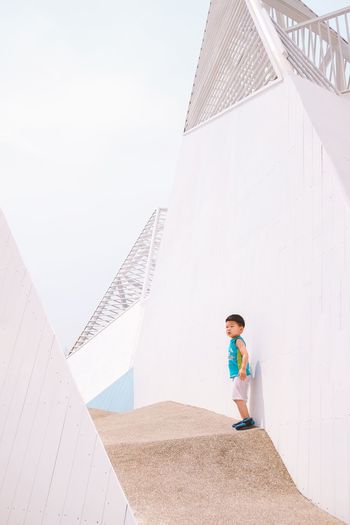 Boy walking by building against sky
