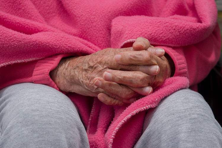 Hands of a old woman with pink blanket
