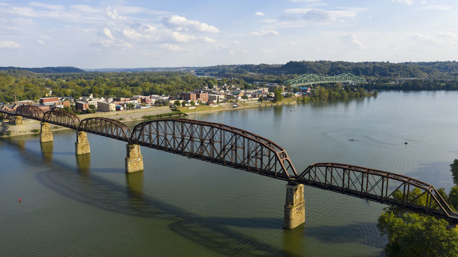 Bridge over river in city against sky