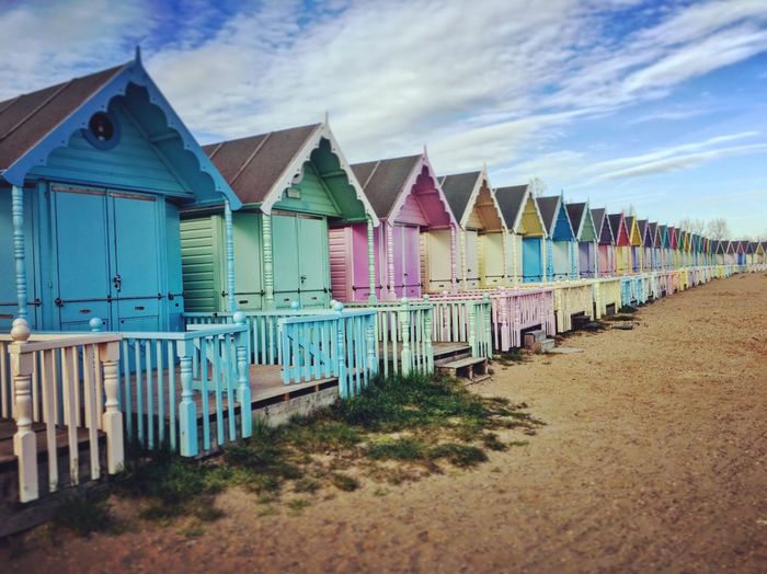 View of colorful, pastel coloured beach huts against blue sky