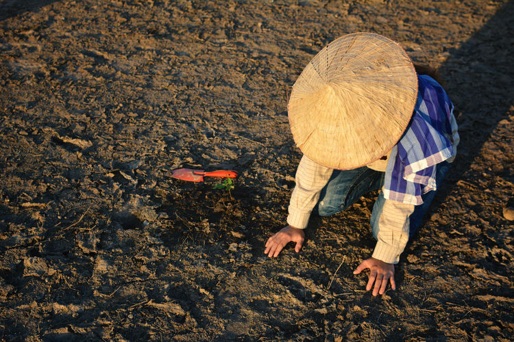 Woman planting while crouching on field