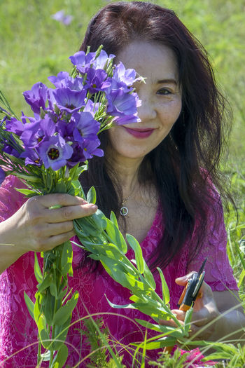 Portrait of woman holding purple flowering plant
