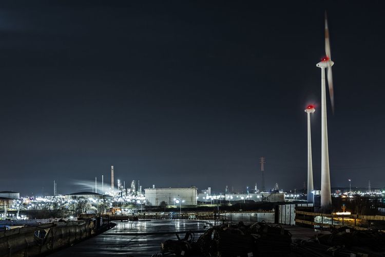 View of windmill by harbor against sky