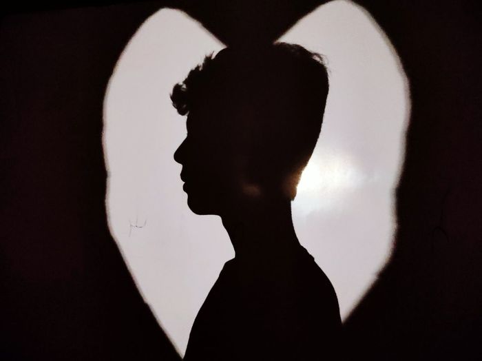 Close-up portrait of silhouette man standing against black background