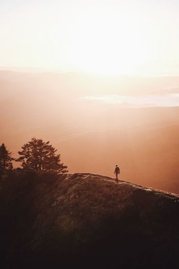 SILHOUETTE PERSON STANDING ON MOUNTAIN AGAINST SKY DURING SUNSET