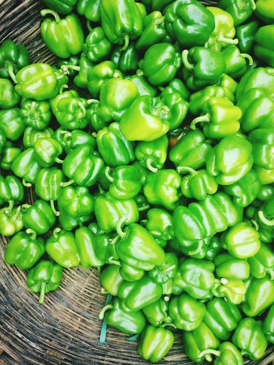 Directly above view of green bell peppers in wicker basket for sale