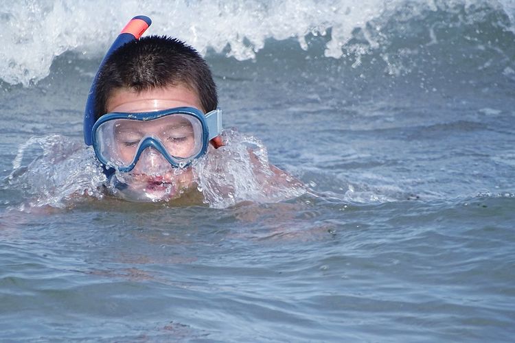 Boy wearing scuba mask while swimming in sea
