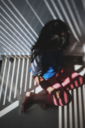 High angle view of girl sitting on wall at home