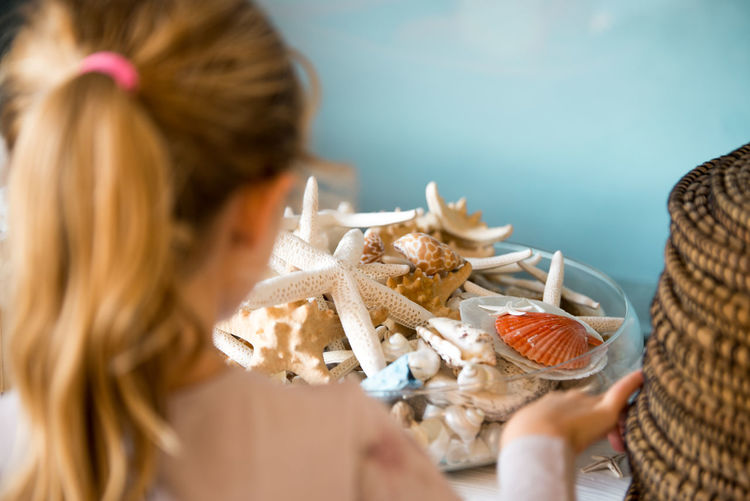Close-up of blonde girl with seashells in home