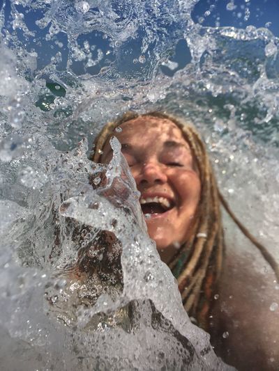 Cheerful woman splashing sea waves