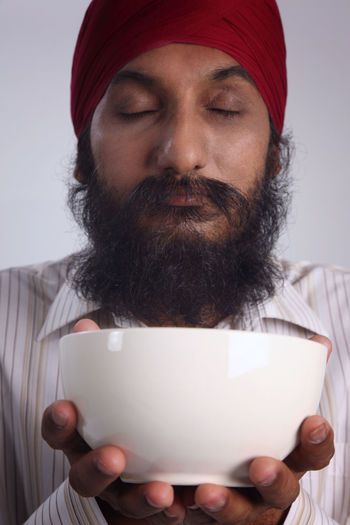 Close-up of bearded man with eyes closed holding bowl