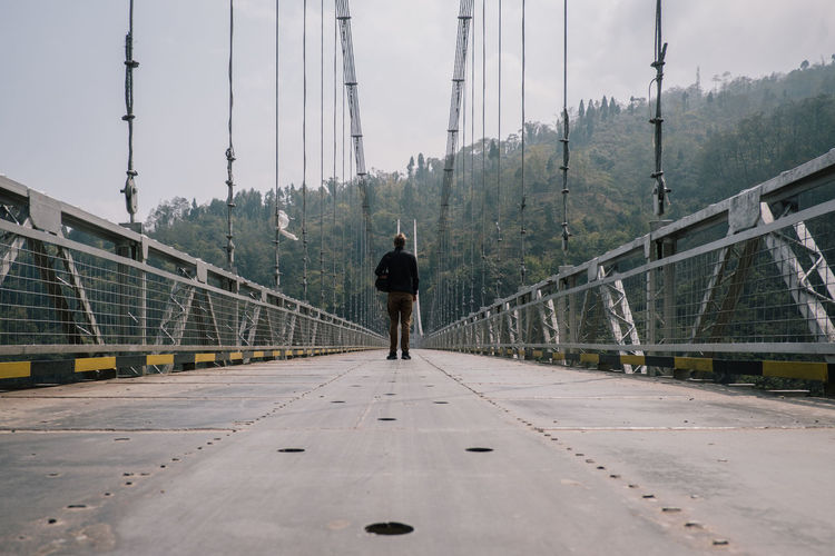 Rear view of man standing on footbridge