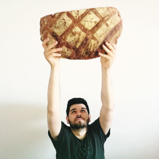 Portrait of man holding bread against white background