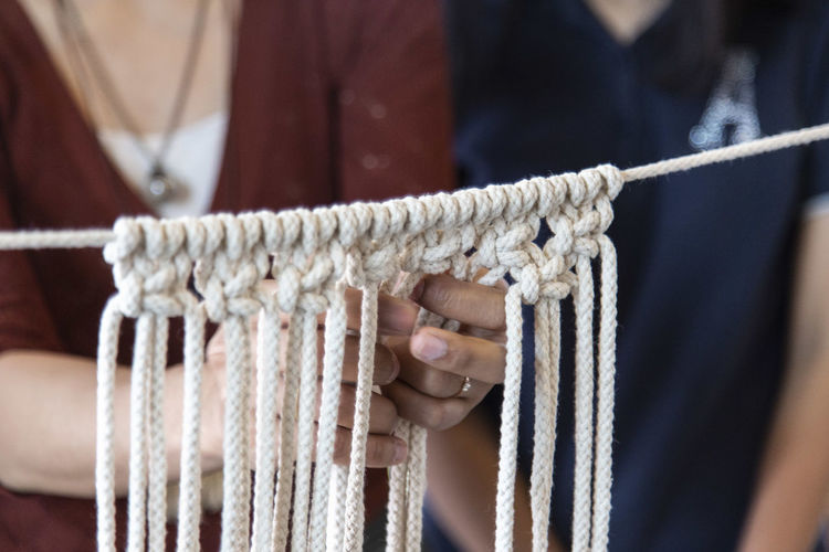 Midsection of women doing macrame