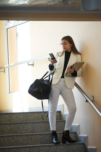 Young businesswoman using smartphone while standing