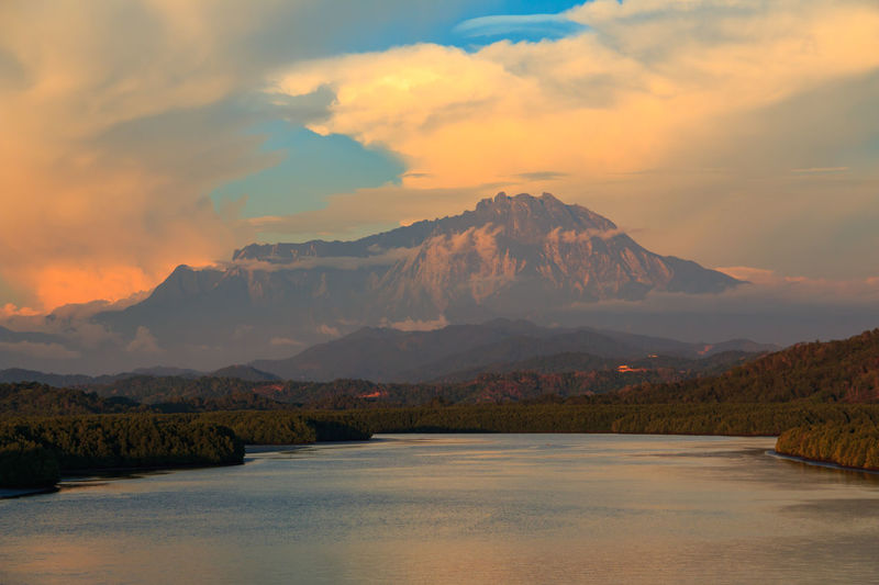 Scenic view of lake by mountains against sky during sunset