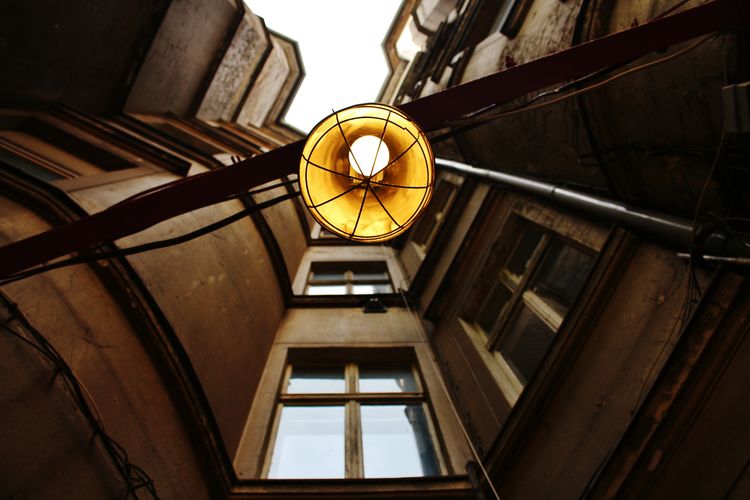 Low angle view of illuminated lamp hanging on ceiling of building