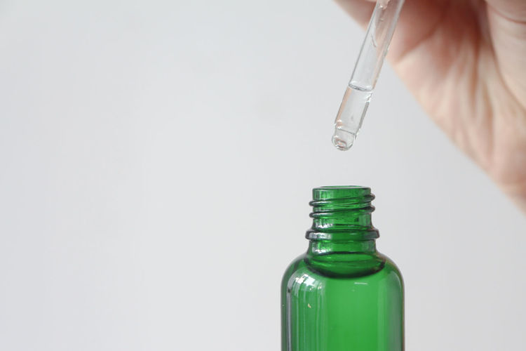 Close-up of syringe in bottle against white background
