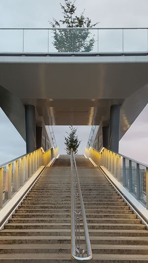 Steps by railroad bridge against sky