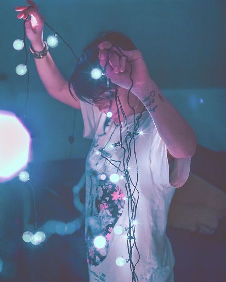 Portrait of woman holding fairy lights at night