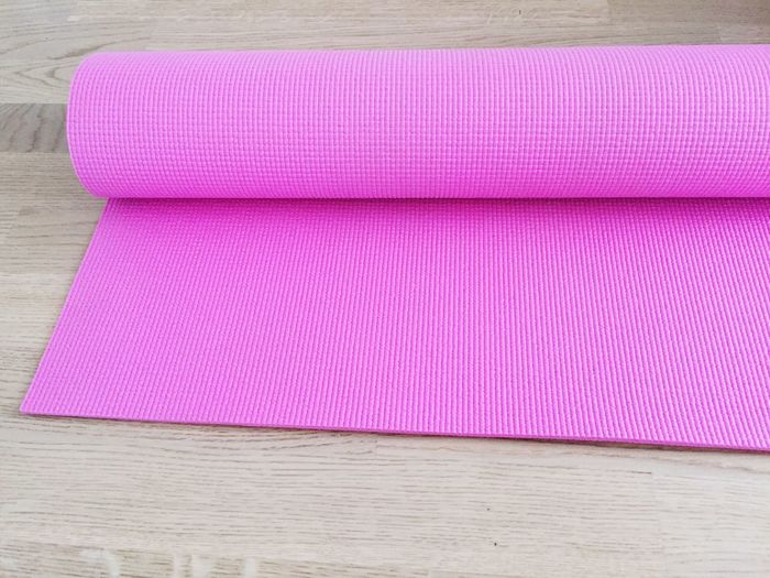 High angle view of pink yoga mat on wood