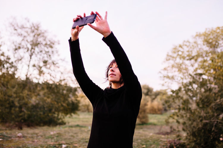Smiling woman doing selfie while standing at park