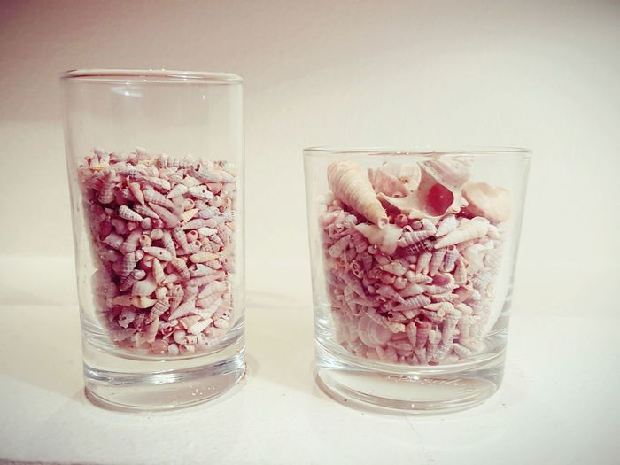 Close-up of conch shells in glasses on table