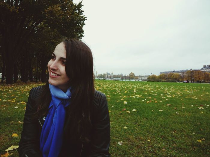 Portrait of smiling young woman on field against sky
