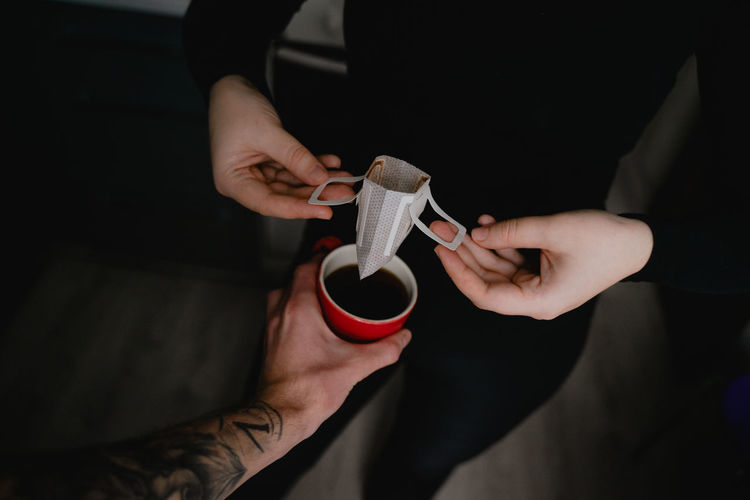 Holding coffee mug over paper filter, coffee brewing concept