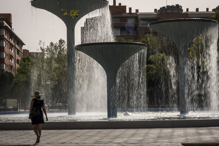 Rear view of man by fountain against sky