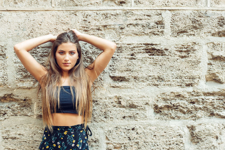 Portrait of a young woman standing against wall