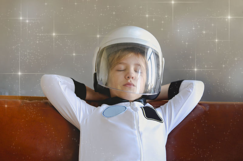 Boy wearing astronaut costume while sleeping on sofa