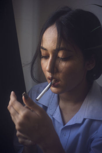 Close-up portrait of a young woman smoking