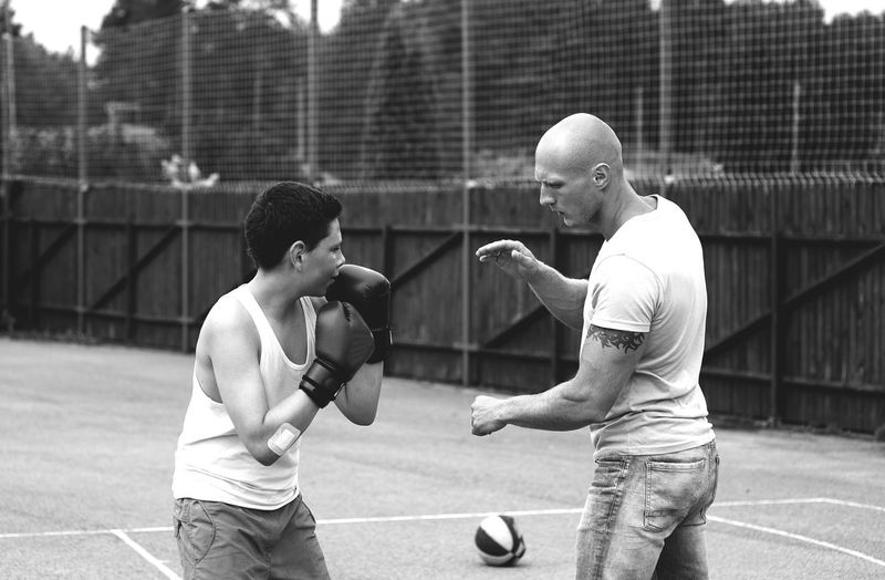 Side view of young male trainer teaching boxing to boy