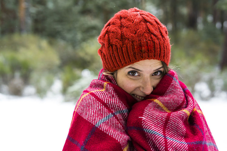 Portrait of young woman in red knit hat standing outdoors during winter