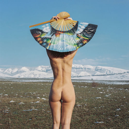 Rear view of shirtless man standing against mountain