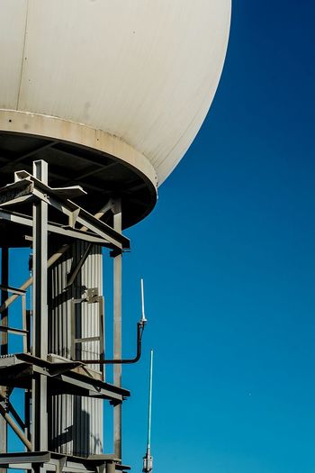 Low angle view of radar station against clear blue sky