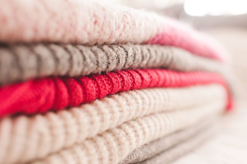 Stack of bright color knitted clothes on shelf in store close up. warm and cozy colorful sweaters. 