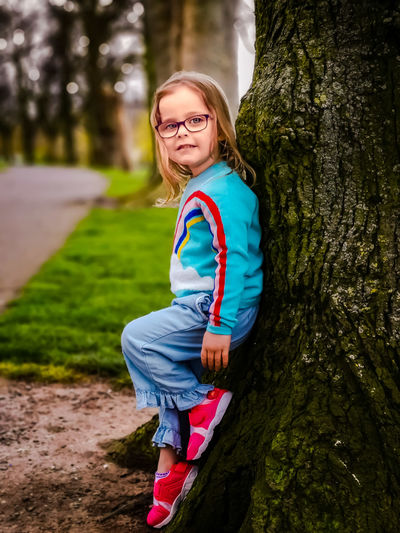 Portrait of smiling girl leaning on tree trunk